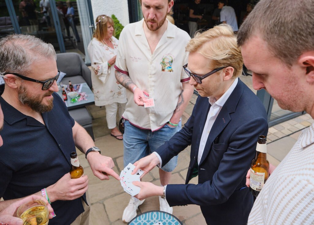 A photo of a close up magic act, wowing party goers at a party by doing a card trick